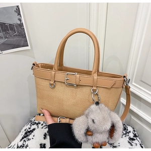 Détail du sac seau en paille beige avec sangle en cuir et breloque lapin en peluche
