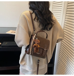 Detail of dark brown vintage backpack with teddy bear charm and striped scarf accessory
