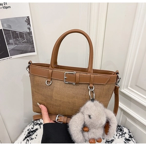 Détail du sac cabas tissé avec garniture en cuir marron et breloque lapin en peluche