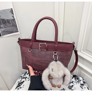 Détail du sac seau bordeaux avec texture tressée et breloque lapin en peluche grise