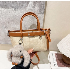 Détail du sac seau tissé avec garniture en cuir marron et breloque lapin en peluche mignonne