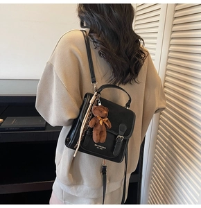 Detail shot of black matte shoulder bag featuring a cute plush bear and striped scarf