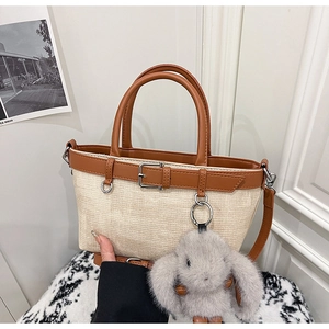 Détail du sac seau en paille avec garniture en cuir marron et pendentif lapin mignon