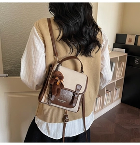 Detail of a beige and brown crossbody bag with a plush bear charm on a female model