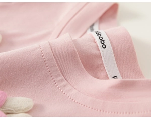 Close-up of pink ribbed cotton neckline with brand label on a soft girl's summer tee