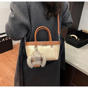 Vue détaillée du sac cabas en paille avec bordure en cuir marron et breloque lapin en peluche