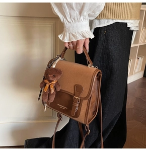 Detail of vintage brown flap crossbody bag with cute bear charm and retro lettered print