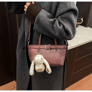 Détail du sac seau marron rouge à texture tressée et charmant lapin en peluche blanc