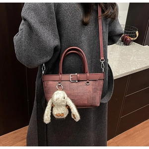 Détail du mini sac cabas marron rouge avec breloque lapin en peluche sur manteau