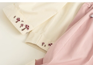 Dettaglio della maglia con ricamo a fungo e pantaloni rosa con vita elastica