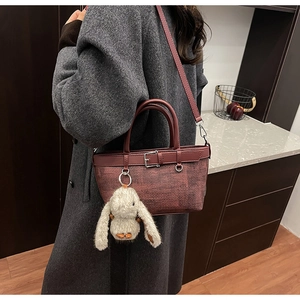 Détail du sac seau rouge vin tressé avec breloque lapin en peluche et boucle argentée