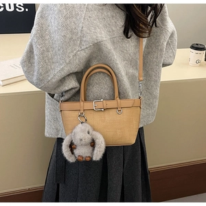 Détail du sac seau tissé kaki avec poignées en cuir camel et breloque lapin en peluche