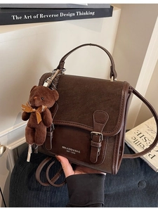 Brown vintage cross-body bag with teddy bear charm and elegant textured leather detail