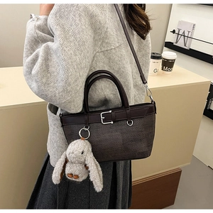 Détail du sac seau tissé marron foncé avec anse en cuir et breloque lapin en peluche