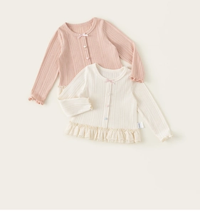 Close-up of pink and white knit cardigans with lace trim and bow detail for girls