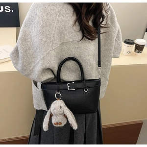 Sac seau tissé noir avec charme lapin en peluche porté par un mannequin dans un café