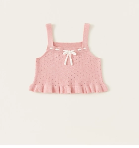 Dettaglio del gilet in maglia rosa per bambine con motivi traforati e fiocco bianco