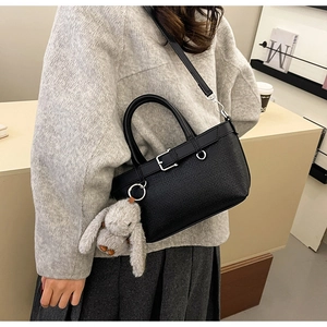 Détail du sac seau en cuir noir texturé avec boucle argentée et breloque lapin en peluche