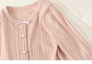 Detail of pink ribbed knit girls shirt with heart buttons and satin bow decoration