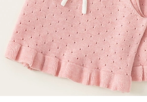 Dettaglio degli shorts neonata in maglia pointelle rosa con volant e coulisse bianca