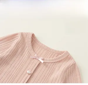 Detail showing the ribbed fabric texture, pink silk bow, and heart button on the collar