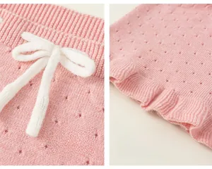 Dettaglio ravvicinato di gilet in maglia rosa da bambina con fiocco bianco e orlo a balze