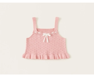 Dettaglio del gilet rosa in maglia per bambina con trama traforata e fiocco bianco