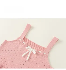 Dettaglio del top rosa in maglia per bambine con trame traforate e fiocco bianco