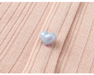 Macro detail of heart-shaped pearlescent button on pink ribbed long sleeve girls t-shirt
