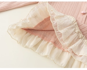 Detail of pink knitted shirt featuring lace trim hem and a heart-shaped button embellishment