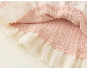 Detail of pink ribbed knit fabric with delicate white chiffon ruffle trim and floral print