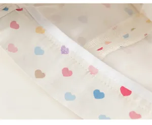 Gros plan détaillé montrant la double couture précise sur tissu avec motifs de cœurs