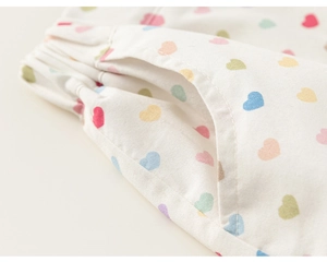 Détail de la taille élastique et de la poche latérale sur un short blanc à cœurs colorés