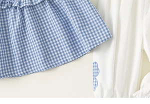 Detail of blue plaid ruffled top and white pants with cloud applique for toddler girls