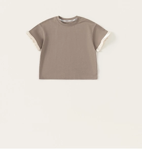 Detail of ruffled lace patchwork on short sleeves of a minimalist taupe cotton T-shirt