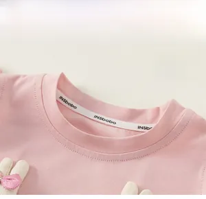 Detail of pink cotton knit T-shirt neckline with round collar and branded inner label