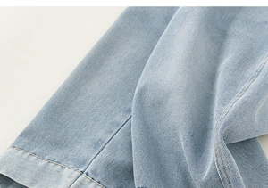 Gros plan sur la texture du denim bleu clair et les coutures de qualité du jean fille