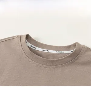 Detailed close-up of ribbed crew neck and decorative inner tape on brown cotton T-shirt
