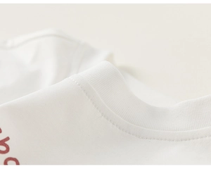 Detailed macro view of the ribbed crew neck and soft cotton fabric on a white boys' T-shirt