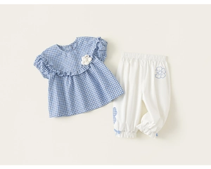 Detail of girls summer plaid top with ruffle collar and white joggers with blue bows