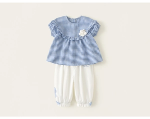 Detail of girls summer plaid top with ruffled edges and white cinched hem casual pants