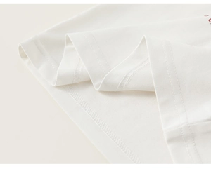 Detail view of cotton t-shirt hem with precise double stitching and red letter print