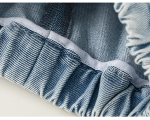Détail des coutures de la taille élastique sur un jean en denim bleu délavé pour filles