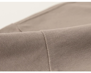 Detailed macro view of soft grey-brown knit cotton fabric texture and neat stitching seam