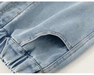 Détail d'un jean bleu clair pour fille avec taille élastique et texture de la poche latérale