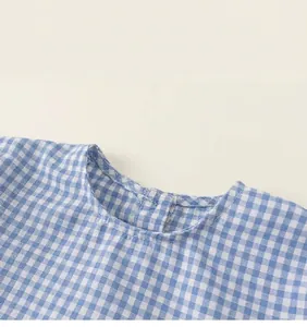 Detail showing blue gingham pattern cotton fabric and back button closure on round neckline