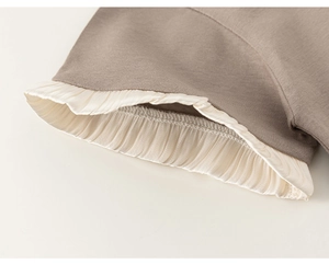 Detail shot of taupe knit sleeve with cream pleated silk ruffle trim for children