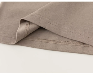 Detailed close-up of double-needle stitching on warm brown cotton t-shirt hemline