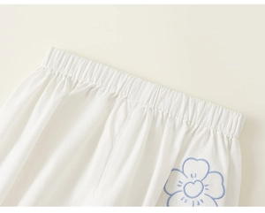 Detail of white cotton shorts featuring elastic waistband and blue flower embroidery