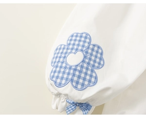 Detail of girl's cotton sleeve featuring blue plaid flower embroidery and bow cuff